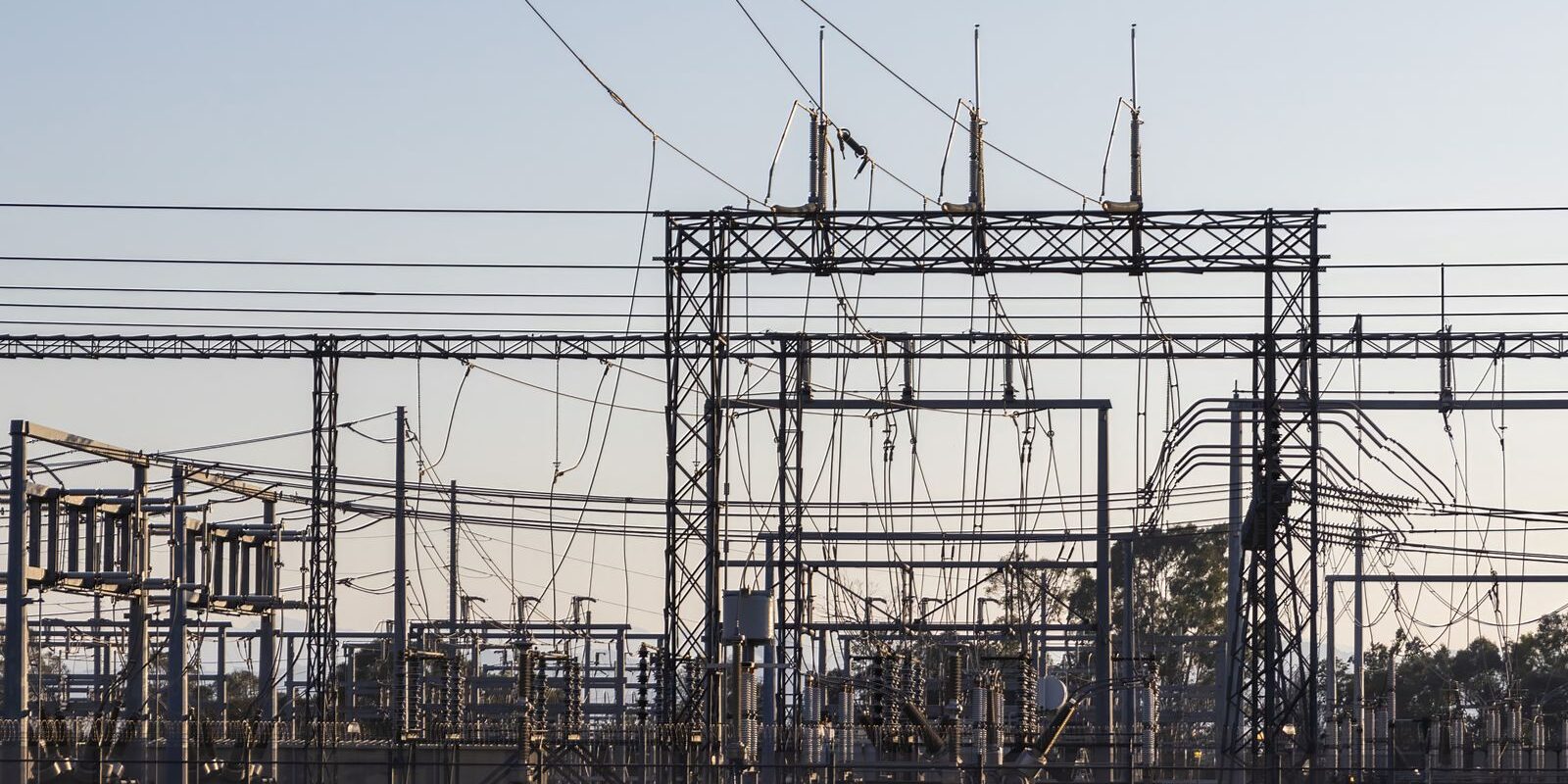 Poste électrique haute tension au crépuscule : portiques, lignes et transformateurs Poste électrique haute tension au crépuscule : portiques, lignes et transformateurs
