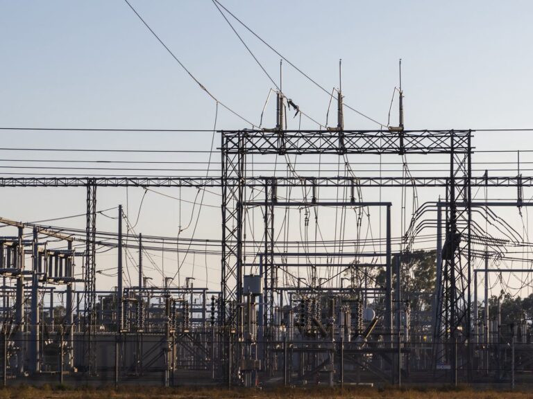 Poste électrique haute tension au crépuscule : portiques, lignes et transformateurs