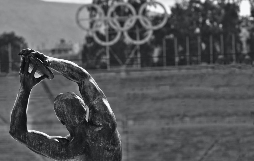 Statue en bronze d'un lanceur de disque devant les anneaux olympiques, en noir et blanc