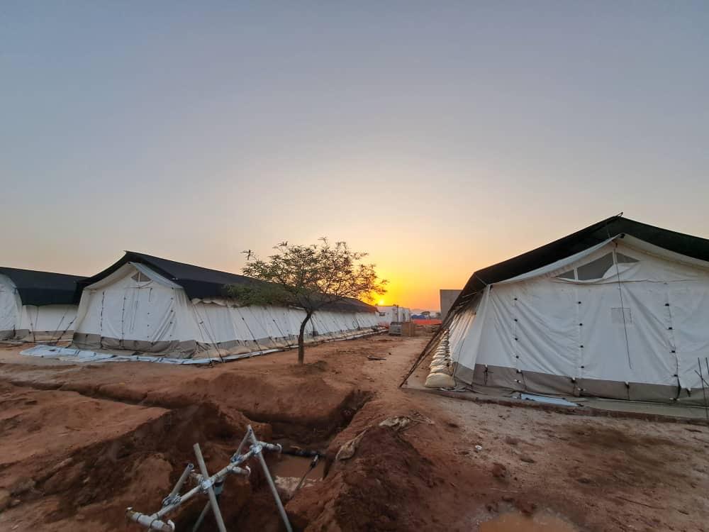 Tchad Camp de tentes humanitaires au coucher du soleil sur un sol de terre rouge